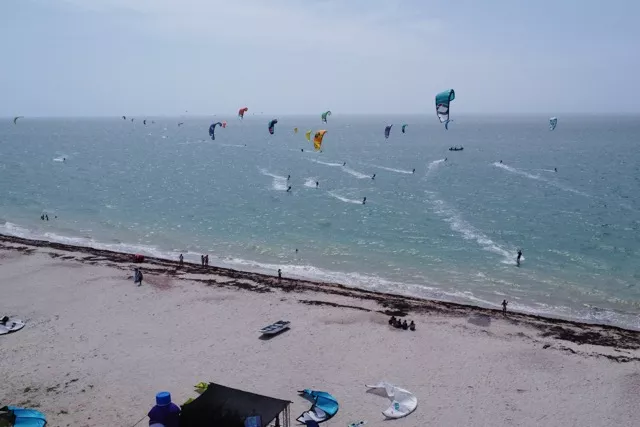 Aerial view of Kite Fest Guajira with multiple kites flying over the beach in Mayapo.